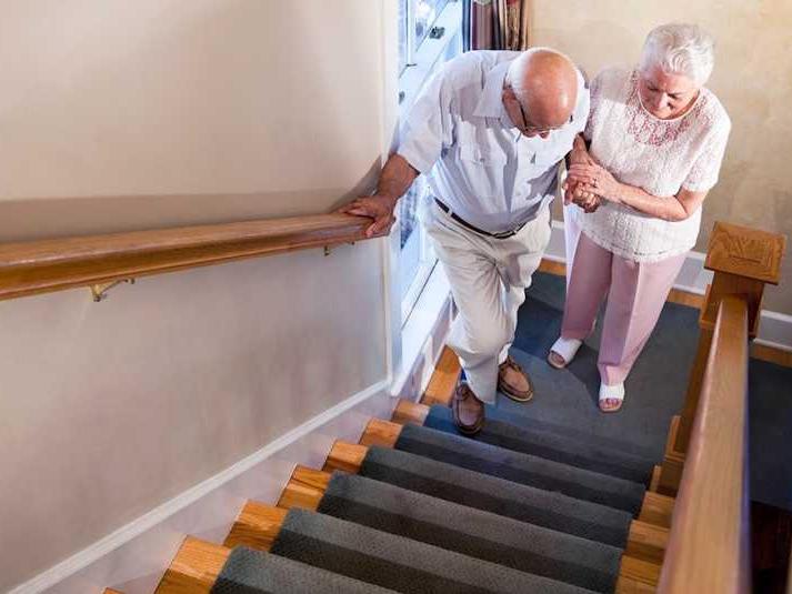 Woman helping a man up the stairs with a railing